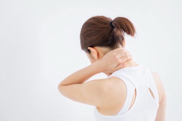 後ろ姿で首の付け根を手で押さえる女性